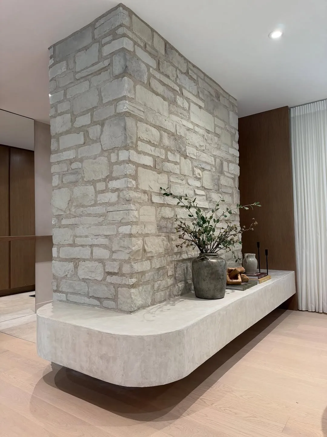 Custom floating bench in microcement running along a reclaimed stone wall.